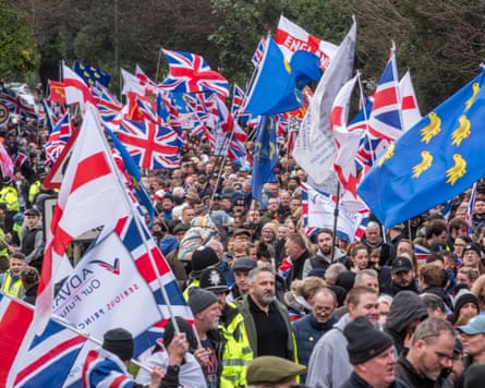 A crowd of marchers, many holding UK or English flags