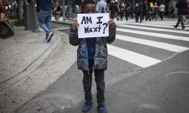 A boy holds a sign during a protest in downtown Los Angeles, Friday, May 29, 2020, over the death of George Floyd, who died in police custody on Memorial Day in Minneapolis. (AP Photo/Christian Monterrosa)