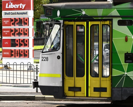 A tram passes signage showing fuel prices at a petrol station in Melbourne