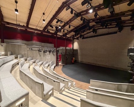 Empty curved auditorium at the Yard theatre, with tiered grey seating facing a brick-walled stage