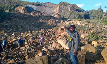 Four people among rocks and rubble with sheared-off mountain in background