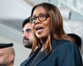 Woman in glasses and blazer speaks into microphone.