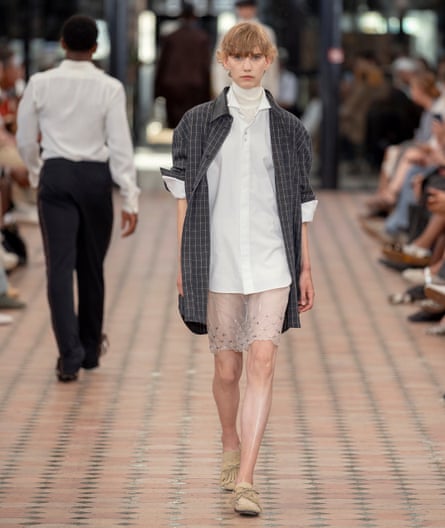 A model wearing a chiffon skirt, white shirt and unbuttoned checked shirt.