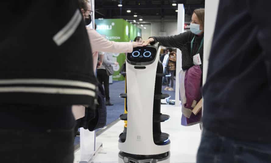 People interact with the BellaBot delivery robot at the Pudu booth at the CES technology show in Las Vegas.