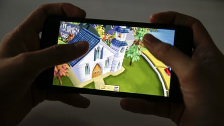 Someone holding a mobile phone playing a video game version of Game of Life.