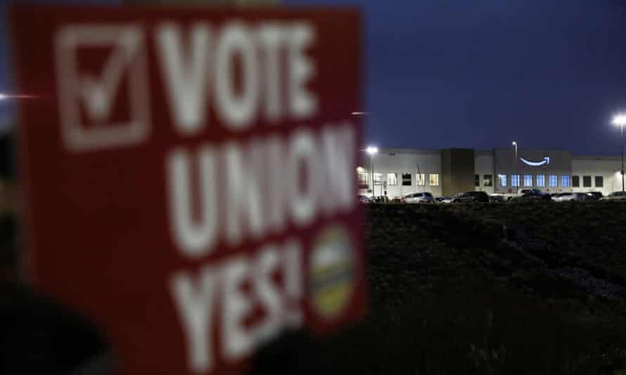 A person holds a sign reading ‘Vote union yes!’ in front of an Amazon facility in Bessemer, Alabama.