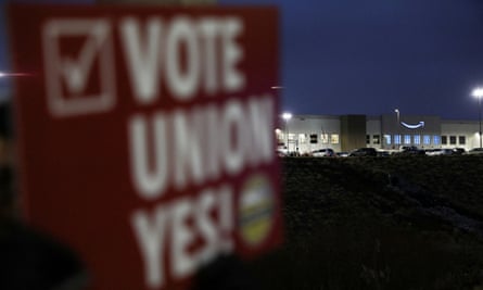 A person holds a sign reading ‘Vote union yes!’ in front of an Amazon facility in Bessemer, Alabama.