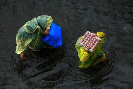 Bangkok residents carry food as they wade through flood waters