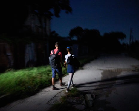 Two children with backpacks on a dark street
