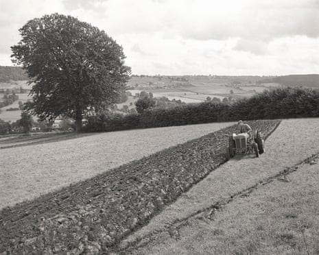 A farmer on a small tractor ploughing a field, England, circa 1950s.