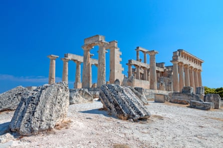 The white columns of an Ancient Greek ruin against a brilliant blue sky