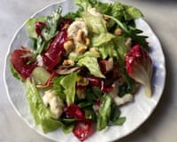 A white plate holds a leafy salad with radicchio, gorgonzola, and toasted hazelnuts