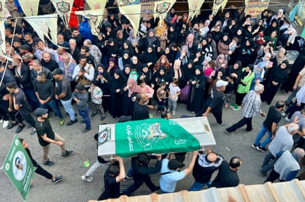 People watch as a coffin is carried through the street.