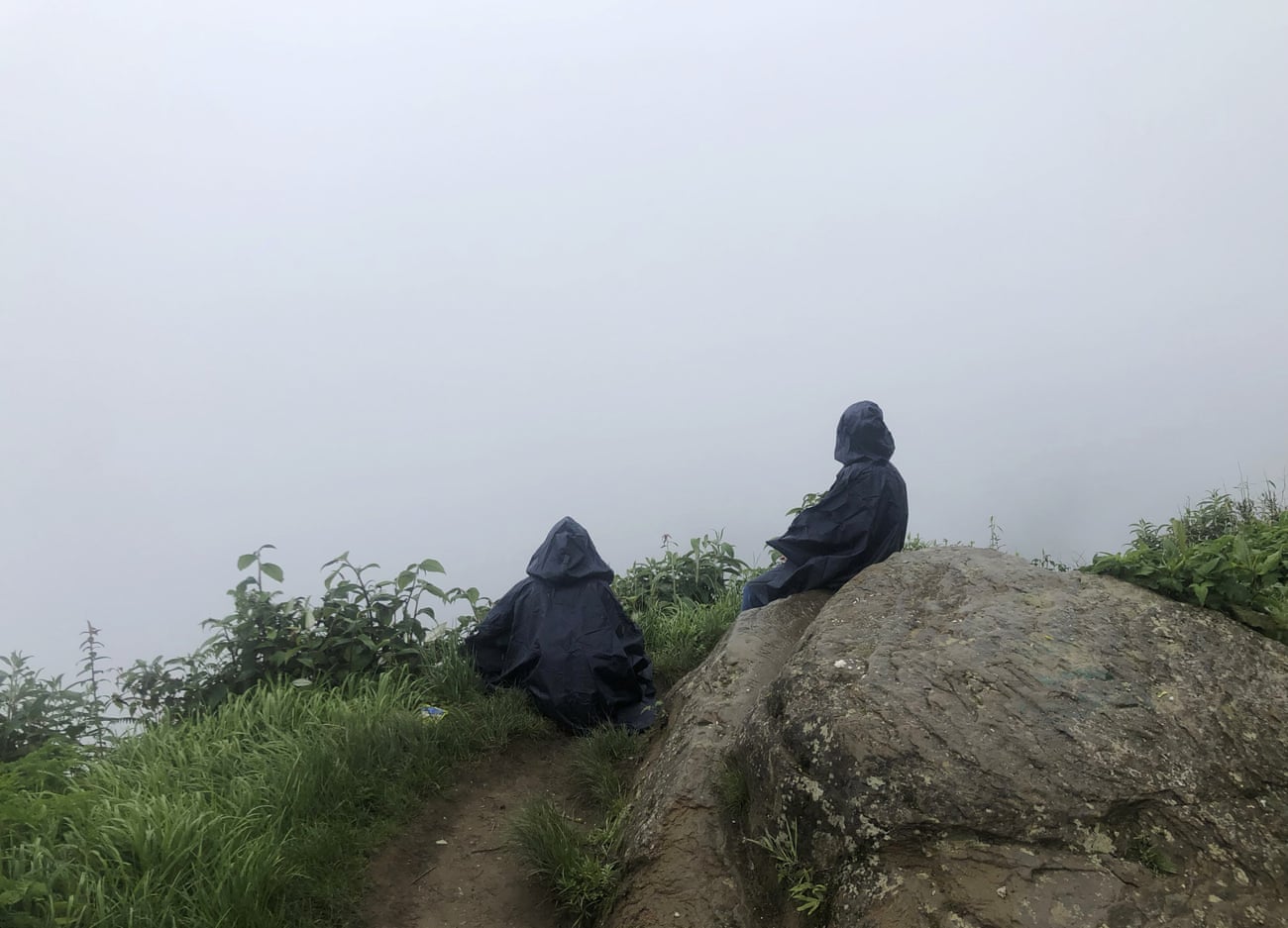 A mother and daughter look out into the clouds over the Dzukou valley, along the Nagaland-Manipur state border, India