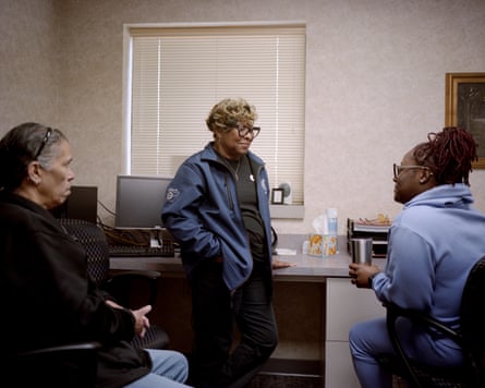 Two women and a man talk in an office.