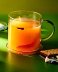 A mulled AJ, in a glass mug, garnished with a s’more. A s’more sits at its base.