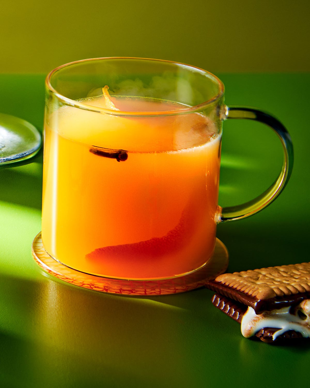 A mulled AJ, in a glass mug, garnished with a s’more. A s’more sits at its base.