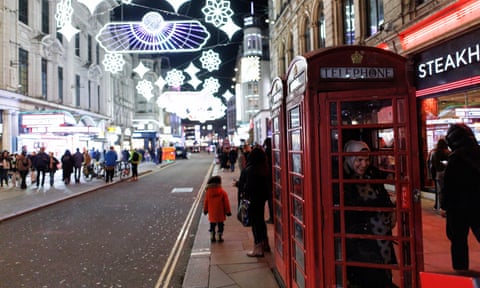 A woman poses for a photograph in a telephone booth in front of the lights