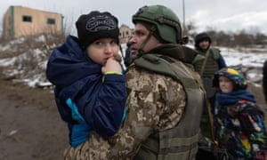 A child is carried by a member of the Ukrainian defence force as residents of Iripin attempted to flee the city yesterday.