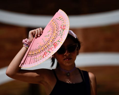 A woman protects herself from the sun with a fan during the first heatwave of the summer in Seville, Spain.