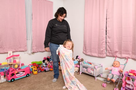 A mother looks a her young child wrapped in a blanket and smiling.