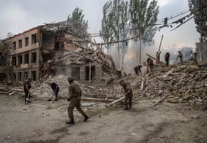 Rescuers and servicemen work at a school building damaged by a Russian military strike in Kramatorsk