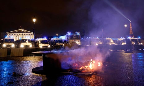 Material burns in front of police vans stationed along a barrier in front of the national assembly near Place de la Concorde in Paris.