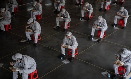 Workers at Dongfeng Honda in Wuhan eat lunch while maintaining a safe distance.