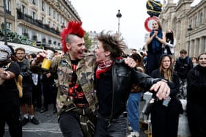 A person with a red mohawk dances another person in the middle of a road with other protesters standing nearby