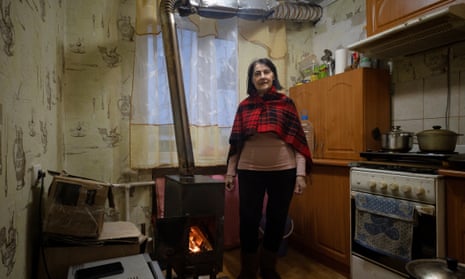 Alina Platonova, 75, stands next to her self-installed wood stove in the kitchen of her apartment that lacks heating, water and gas in the frontline town of Lyman.
