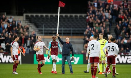 A West Ham supporter stands on the pitch holding a corner flag aloft as ugly scenes overshadowed the match.