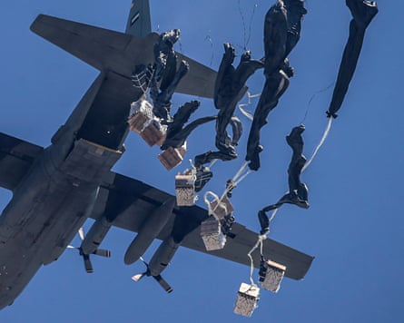 Parachutes begin to unfurl as box of aid are drop from the back of a transport plane