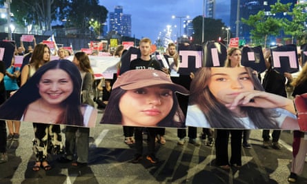 People hold placards and portraits of hostages during a demonstration in a Tel Aviv street at twilight