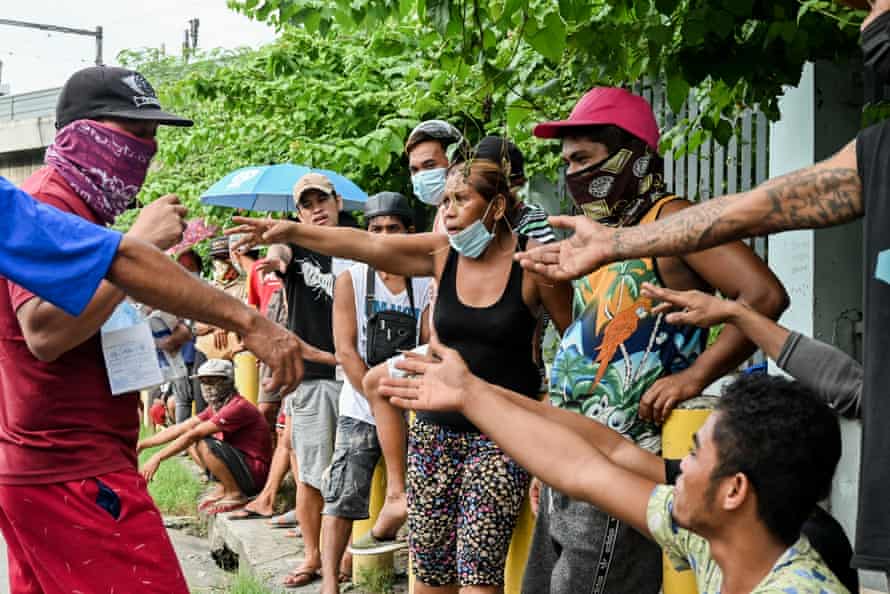 A Kalinga Center representative distributes face masks as hundreds of homeless line up to get food and hygiene packs.