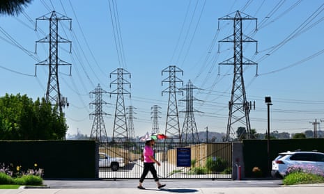 A pedestrian uses an umbrella to shield themself from the hot sun while walking past power lines in Rosemead, California.