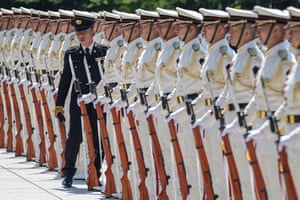 A senior member checks an honour guard standing in formation before the arrival of the Japanese prime minister