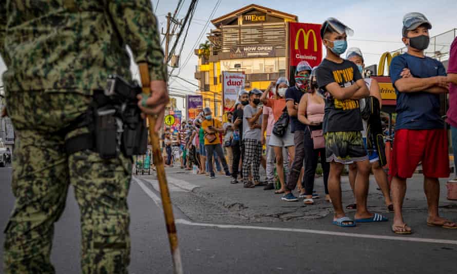 People hoping to get vaccinated against Covid-19 queue outside a health centre in Las Piñas, Metro Manila, Philippines.
