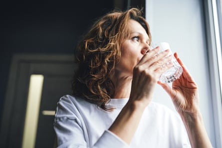 Woman drinking water for daily hydration and wellnessWoman drinking fresh water from a glass, promoting health and wellness