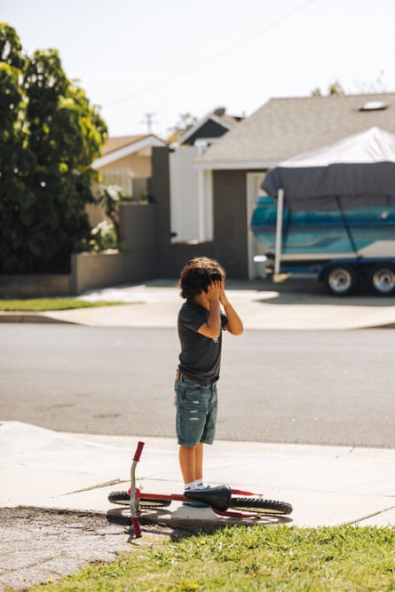 A child plays in a driveway with a bicycle at his feet.