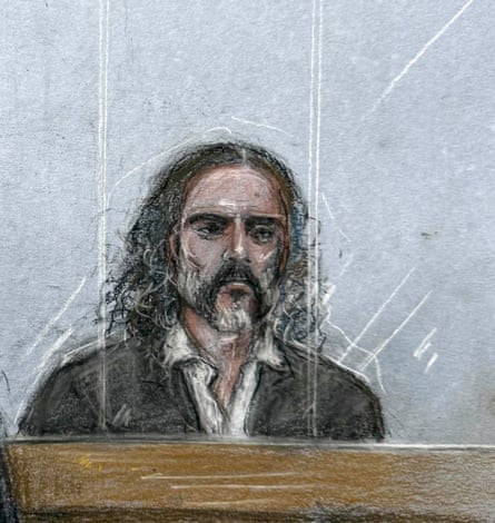 Court sketch of Russell Brand standing at a wooden dock behind glass during jury selection
