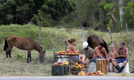 A family of farmers selling mangoes wait for customers at the side of a road on the outskirts of Havana.