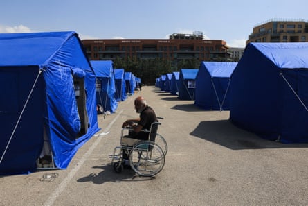 A displaced man in a wheelchair surround by blue tents