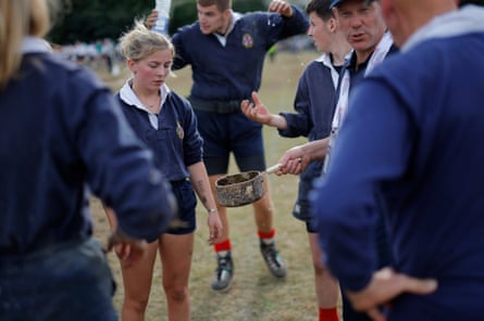 The coach for the Scottish U23 mixed 560kg team holds out an old pan containing sticky resin for people to use on their hands.