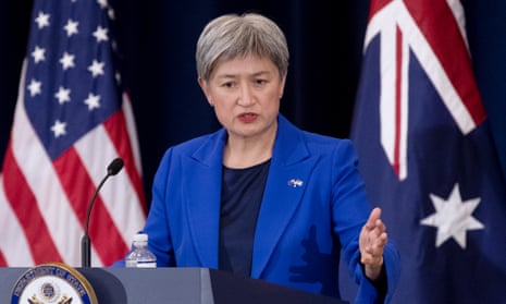 Penny Wong addressing the media from a lectern in front of Australian and US flags