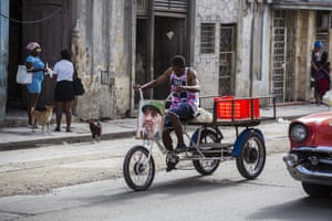 A man rides a tricycle decorated with a picture of Castro
