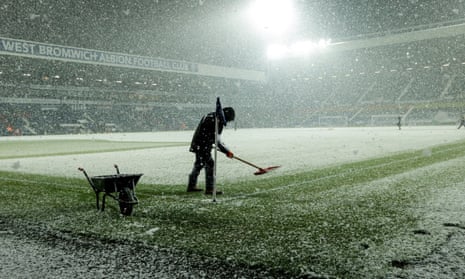 Grounds staff clear the snow off the pitch.