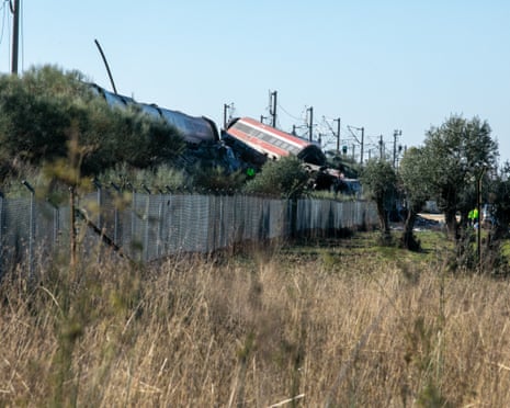 Derailed train carriages lie toppled near Urda, Spain, with emergency workers in the distance