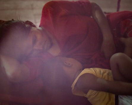 A woman lies on her side next to a baby