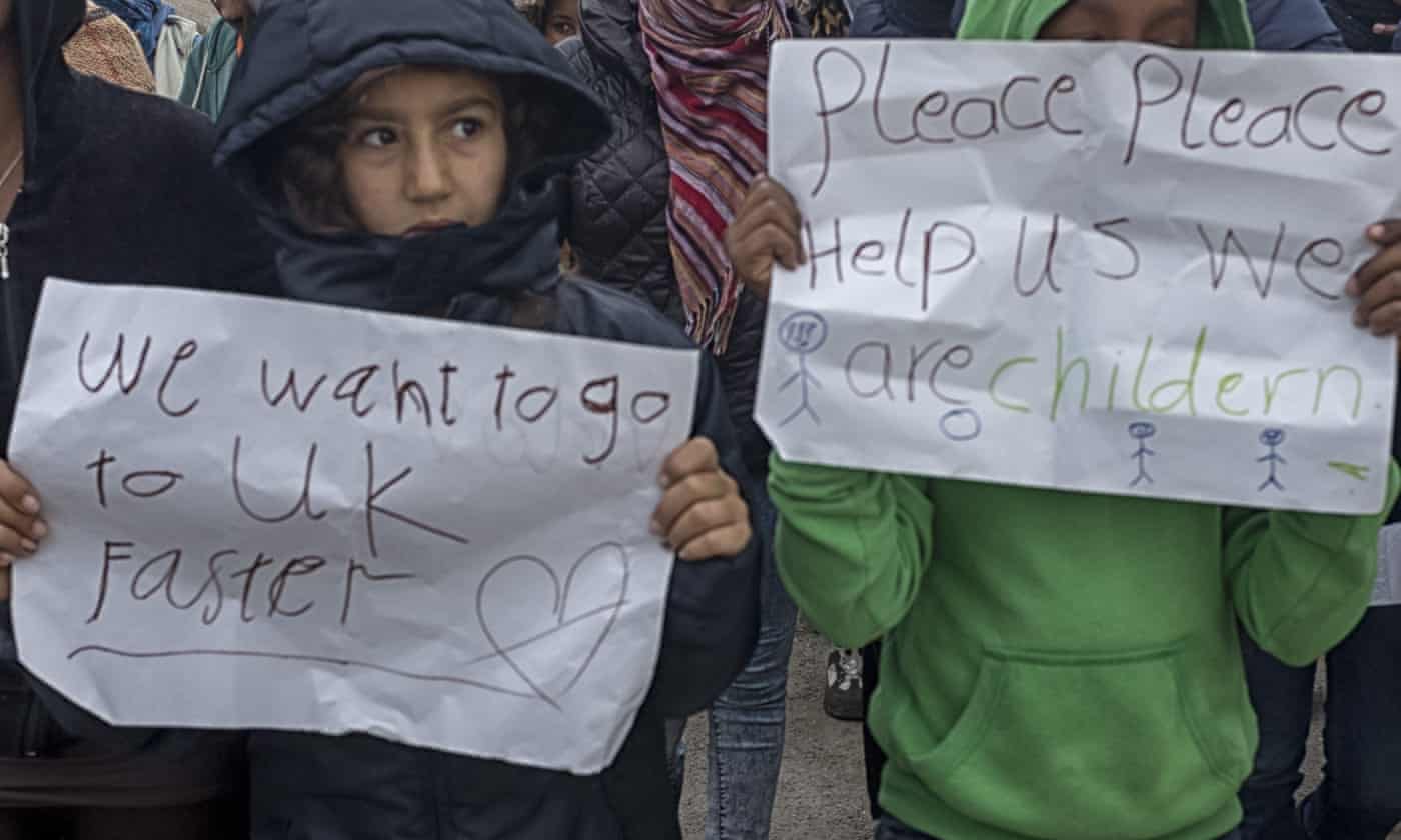 Children at the Calais refugee camp hold up handwritten signs, asking for help
