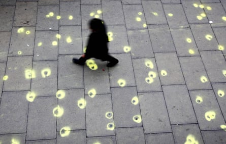 person walks on sidewalk covered in small wads of gum encircled with bright yellow chalk